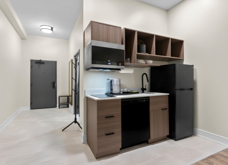 Hotel kitchen near Monmouth Mall, showcasing a refrigerator, microwave, and sink for guest use.