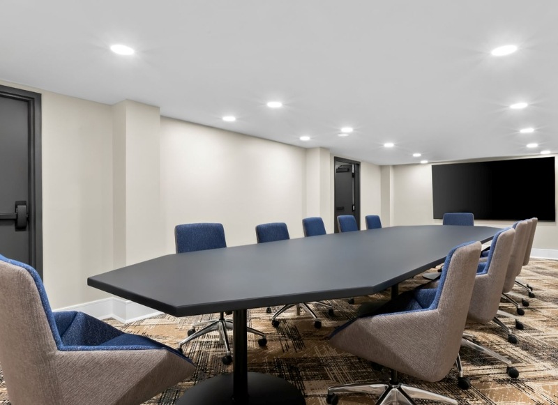 A spacious conference room with seating and a large screen, suitable for meetings and events.