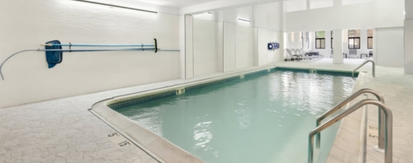 Hotel Near Monmouth Medical Center Bright indoor hotel swimming pool with lounge chairs and cleaning equipment on the wall.