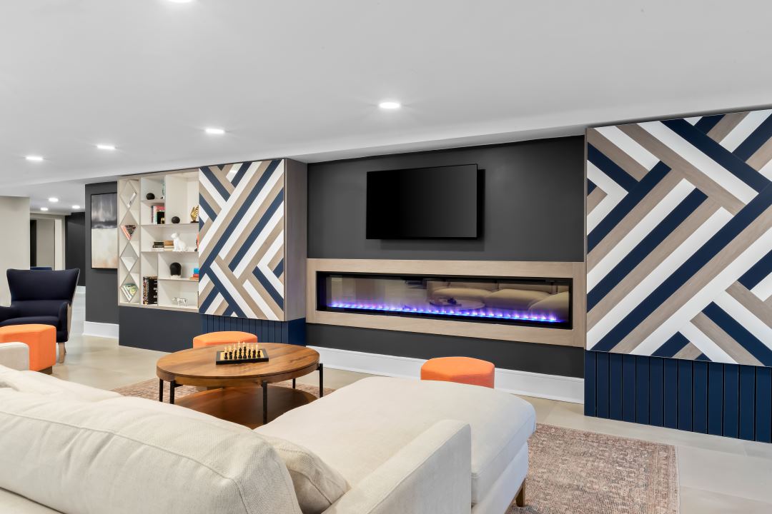 Lobby-3 Modern hotel lounge with a white sofa, linear fireplace, TV, and decorative wall panels.