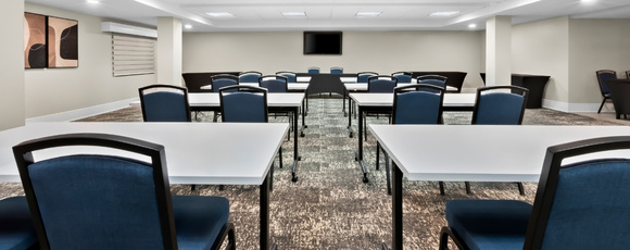Modern meeting room with tables and seating for events at Latitude Suites
