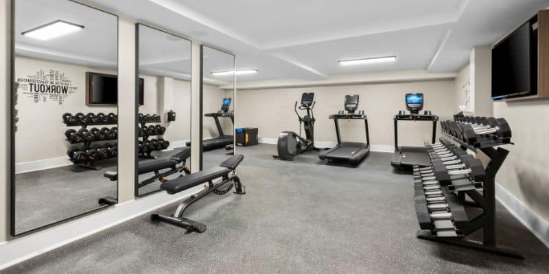 Fitness center at Latitude Suites with cardio equipment and weights for long-term stay guests