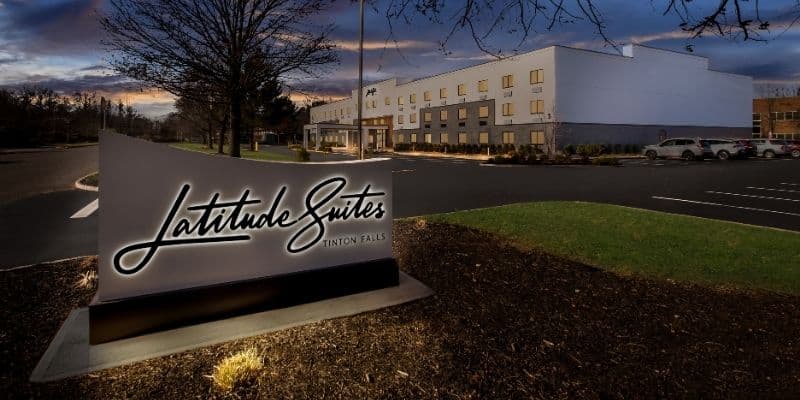 Latitude Suites Tinton Falls exterior and illuminated hotel sign at dusk